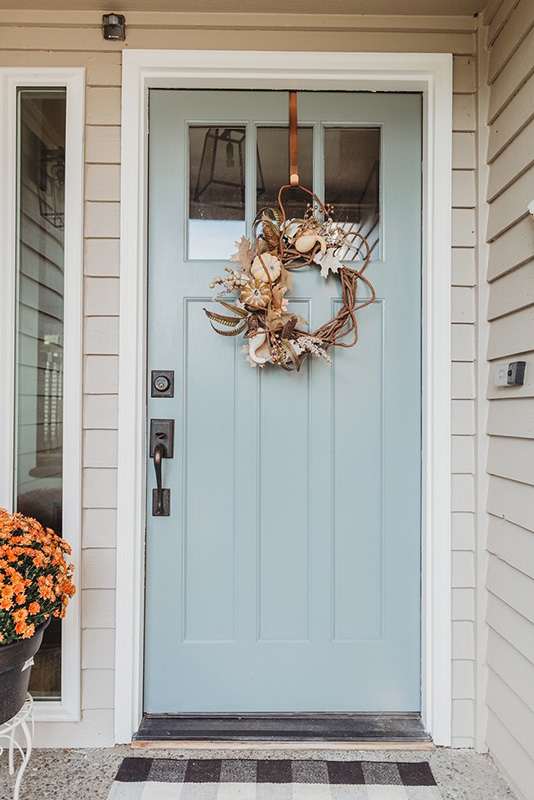 Light blue front door decorated with a seasonal wreath.