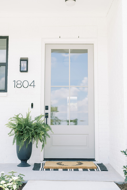 Neutral toned front door with large glass panels and a planter.