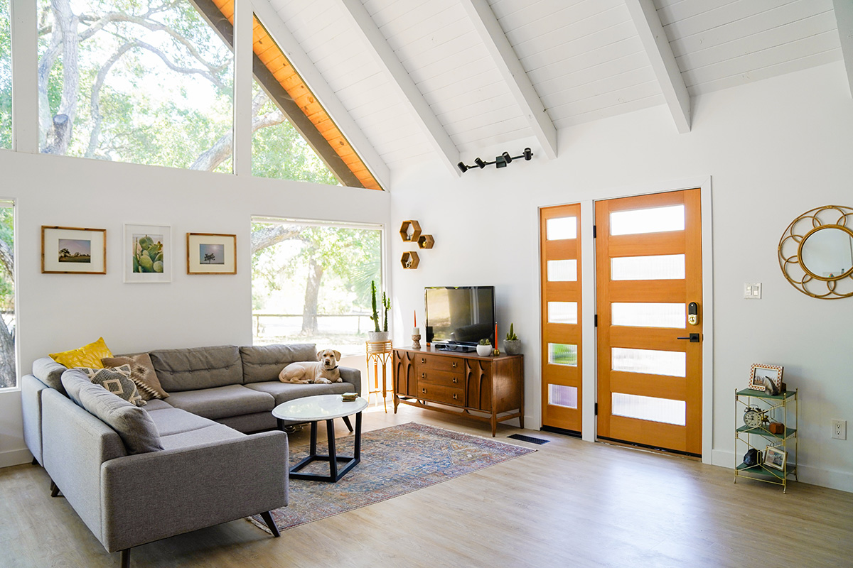 Living room with natural light from large windows and modern entry door.