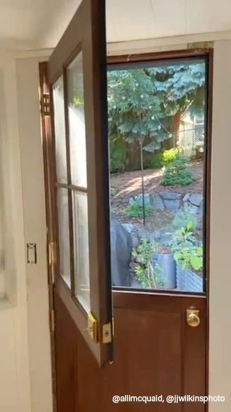 A Dutch door featuring a window, showcasing a vibrant garden outside.