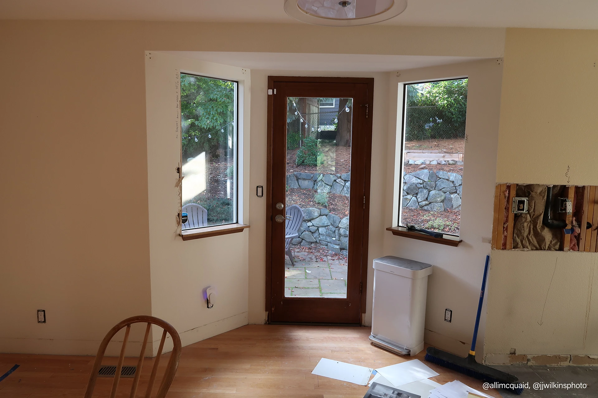 A room featuring a window on one wall and a door on the opposite side, with neutral-colored walls and flooring.